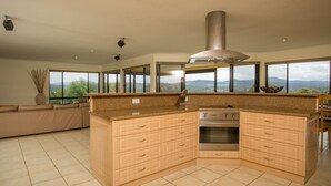 Cozinha moderna com ilha central, forno embutido e amplas janelas com vista para o exterior.