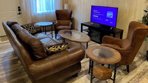 A living room with a brown leather sofa, two armchairs, a coffee table, and a TV displaying a welcome message. - Private Spacious Unit. King bed/2 twin xl beds (Citrus Heights)