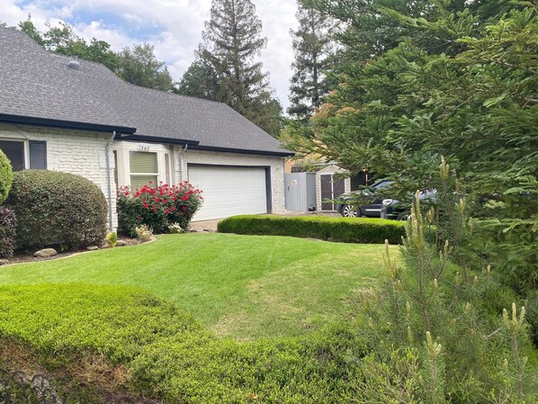 Uma casa residencial com gramado bem cuidado, garagem e entrada para carros.