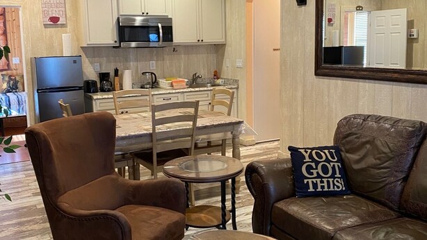 A modern kitchen with white cabinets, a microwave, and a dining area with a table and chairs. - Private Spacious Unit. King bed/2 twin xl beds (Citrus Heights)