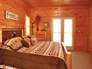Cozy bedroom with a large bed, dresser, and window offering a view of the outside.