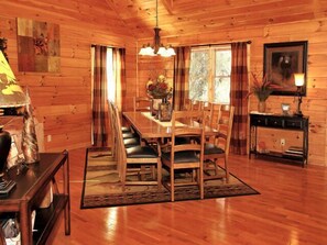 Cozy cabin-style interior with a dining table, staircase, and fireplace.