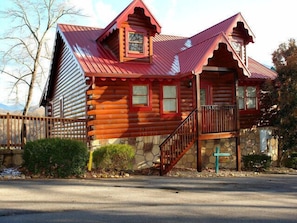Cozy cabin with a front porch and wooden staircase.