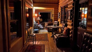 Interior de una cabaña de troncos con una zona de estar acogedora, una chimenea y una mesa de comedor.