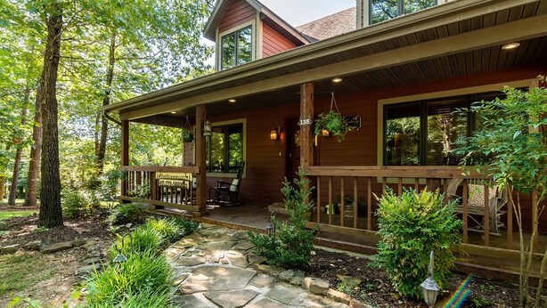 Une maison en bois avec un chemin de pierre menant à un porche doté d’un espace salon extérieur.