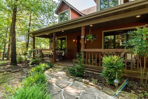A wooden house with a stone pathway leading to a porch with outdoor seating. - Private 40-Acre Cottage, Hot Tub, Pool Table & Car Charger (Blue Eye)