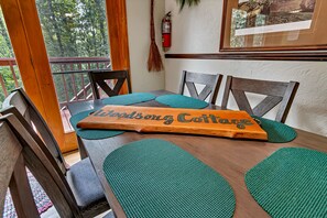 Una mesa de madera con individuales color turquesa y un letrero de madera que dice "Woodsong Cottage".