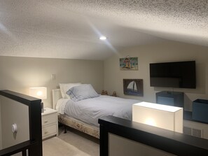 A bedroom with a bed, nightstand, dresser, and a TV mounted on the wall. - Zenful Villa - Beachfront with Private Pool, Private Beach Access & Gulf Views (Santa Rosa Beach)