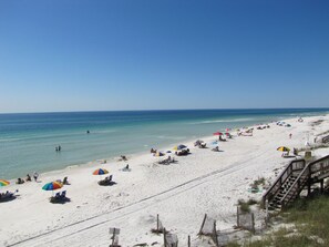 Ein Strand mit Sonnenschirmen, Liegestühlen und einem Holzsteg.