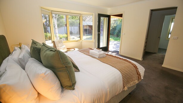 A bedroom with a large bed, a chair, and a view of the outside. - BRIGHT GYPSY: Bright (Bright)