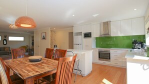 A modern kitchen with white cabinets, a green backsplash, and a built-in oven. - BRIGHT GYPSY: Bright (Bright)