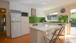 A modern kitchen with white cabinets, a central island, a built-in oven, and a green backsplash. - BRIGHT GYPSY: Bright (Bright)