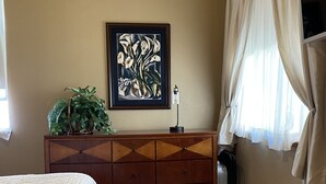 A bedroom with a bed, a dresser, a framed picture, and a window with curtains. - BEAUTIFUL SPACIOUS APARTMENT- 1 Bedroom with Living Room & Kitchen. Sleeps 4. (Monument)
