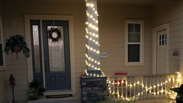 A house with a front porch, a stone pillar, a wreath on the door, and string lights. - BEAUTIFUL SPACIOUS APARTMENT- 1 Bedroom with Living Room & Kitchen. Sleeps 4. (Monument)