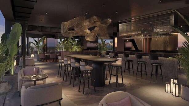 Un bar moderno con barra central, diversas opciones de asientos y una gran escultura abstracta.