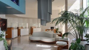 Un vestíbulo moderno con una zona de estar curva, un mostrador de recepción y amplias ventanas que dejan entrar luz natural.
