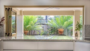 Une cuisine donnant sur un jardin luxuriant, séparé par une clôture en bois.