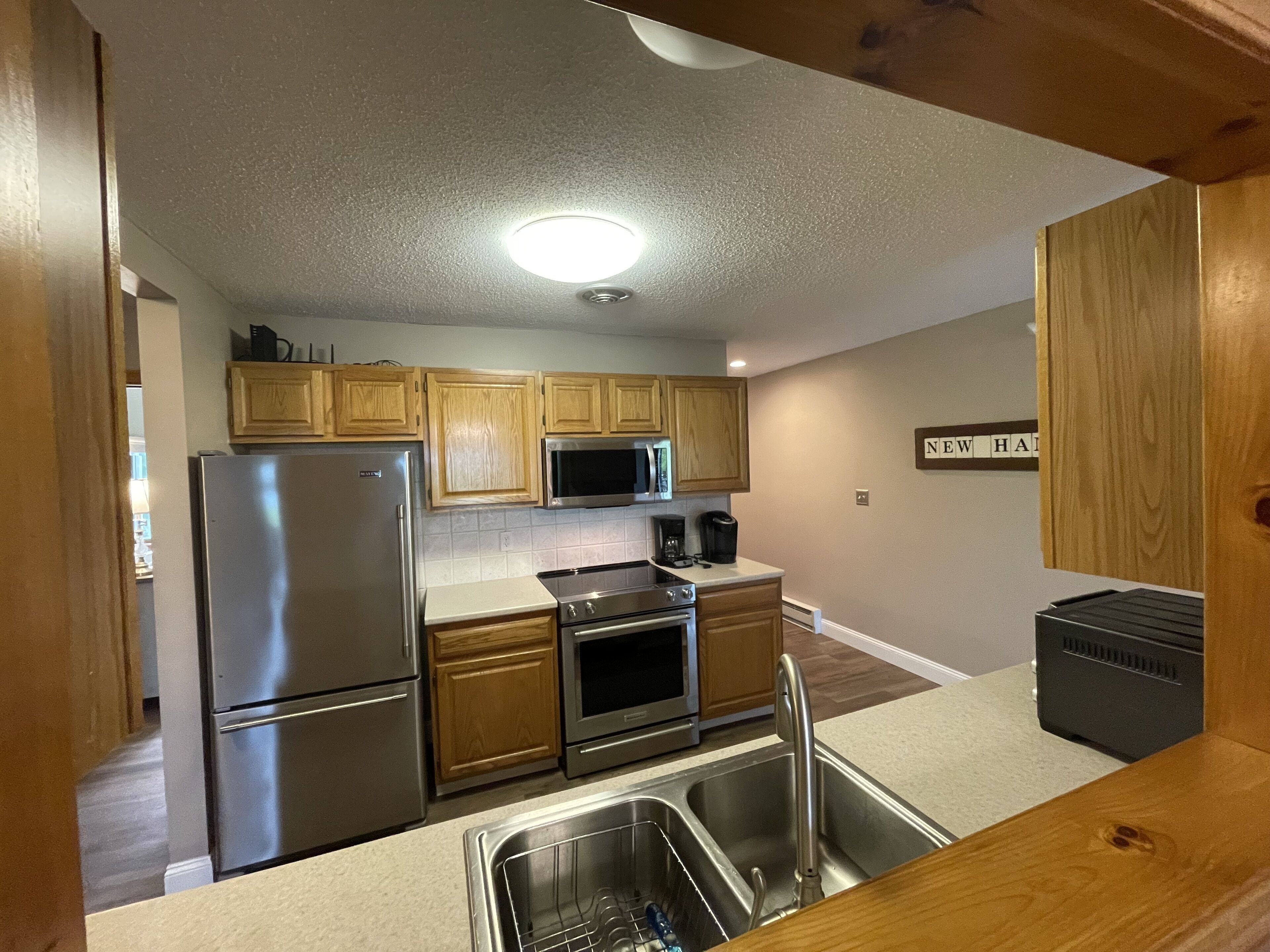 A compact kitchen with wooden cabinets, stainless steel appliances, and a built-in microwave.