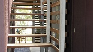 A staircase with wooden steps and white railings, leading to an outdoor area with a view of greenery. - Central location - walking distance to beaches, shops and hotel. (Point Lookout)