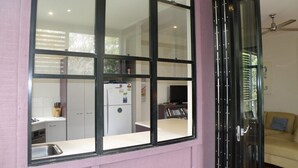 A room with a large window, a door, and a view of a kitchen and living area. - Central location - walking distance to beaches, shops and hotel. (Point Lookout)