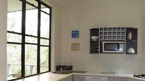 A modern kitchen with a large window, white cabinetry, a microwave, and a dishwasher. - Central location - walking distance to beaches, shops and hotel. (Point Lookout)