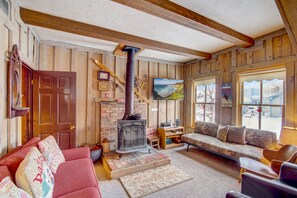 Un salon chaleureux avec une cheminée, des murs en bois, un canapé et un téléviseur.