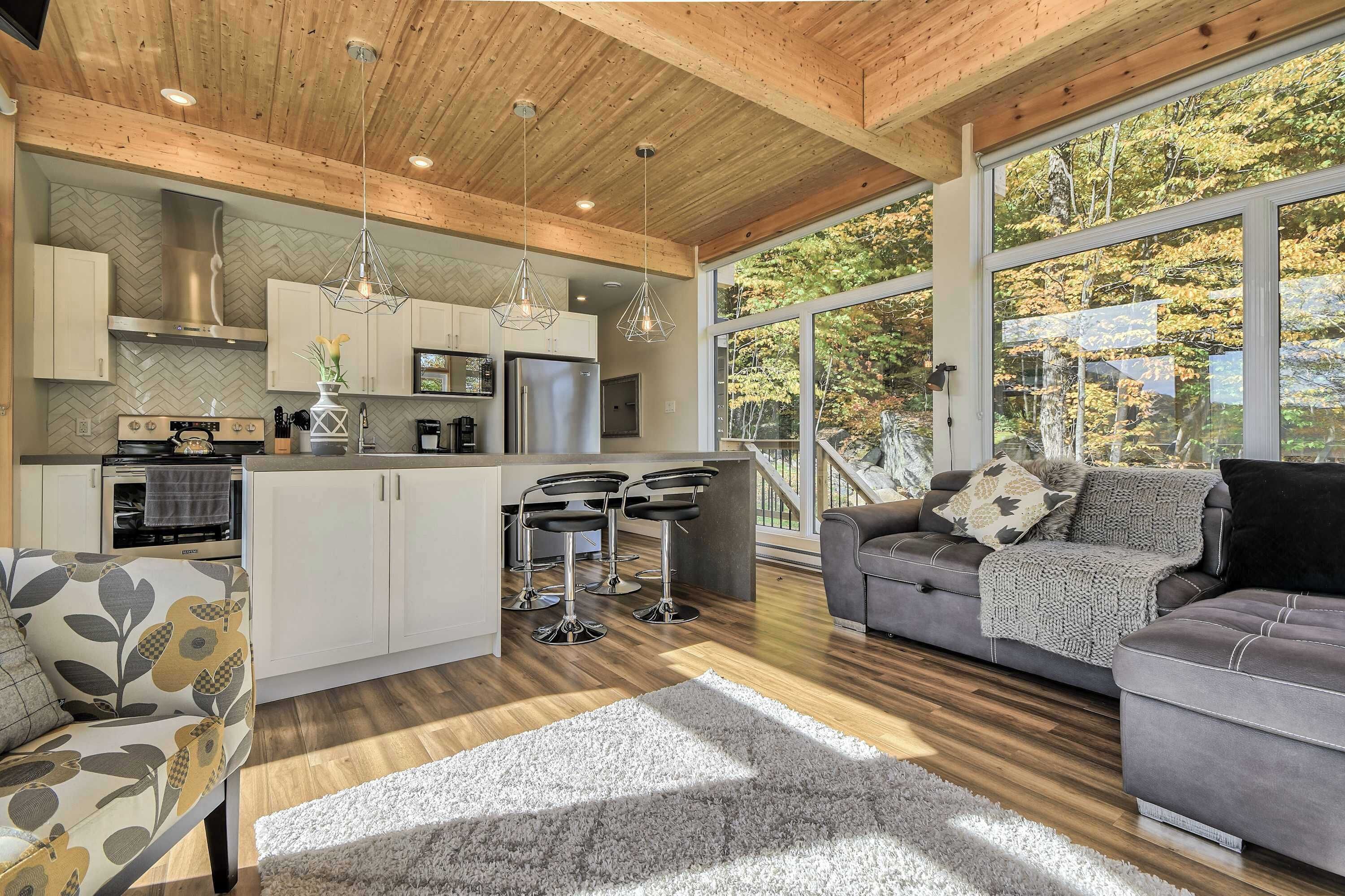 A modern kitchen with a herringbone backsplash, stainless steel appliances, and a central island with bar stools.