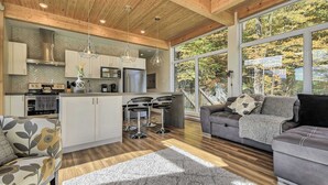 Een moderne keuken met een backsplash in visgraatmotief, roestvrijstalen apparatuur en een centraal eiland met barkrukken.