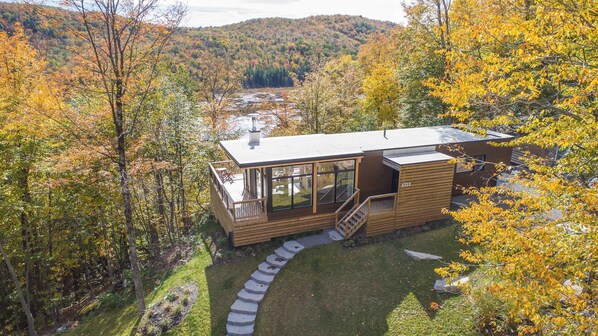 Une cabane dotée d’une terrasse, d’un escalier et offrant une vue sur la forêt environnante.