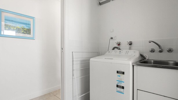 A laundry room with a washing machine, a sink, and a towel rack. - Deepwater Cove Unit 7, 68 Lower Gay Terrace, Bulcock Beach (CALOUNDRA)