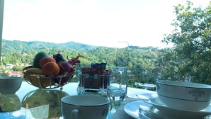 Une table à manger avec un panier de fruits, un verre d’eau et une assiette de nourriture.