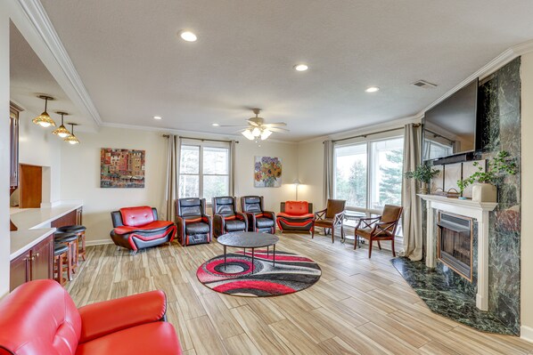 A spacious living room with a fireplace, multiple seating areas, and a large TV mounted on the wall. - Spacious Group Retreat w/ Game Room in Marshall! (Marshall)