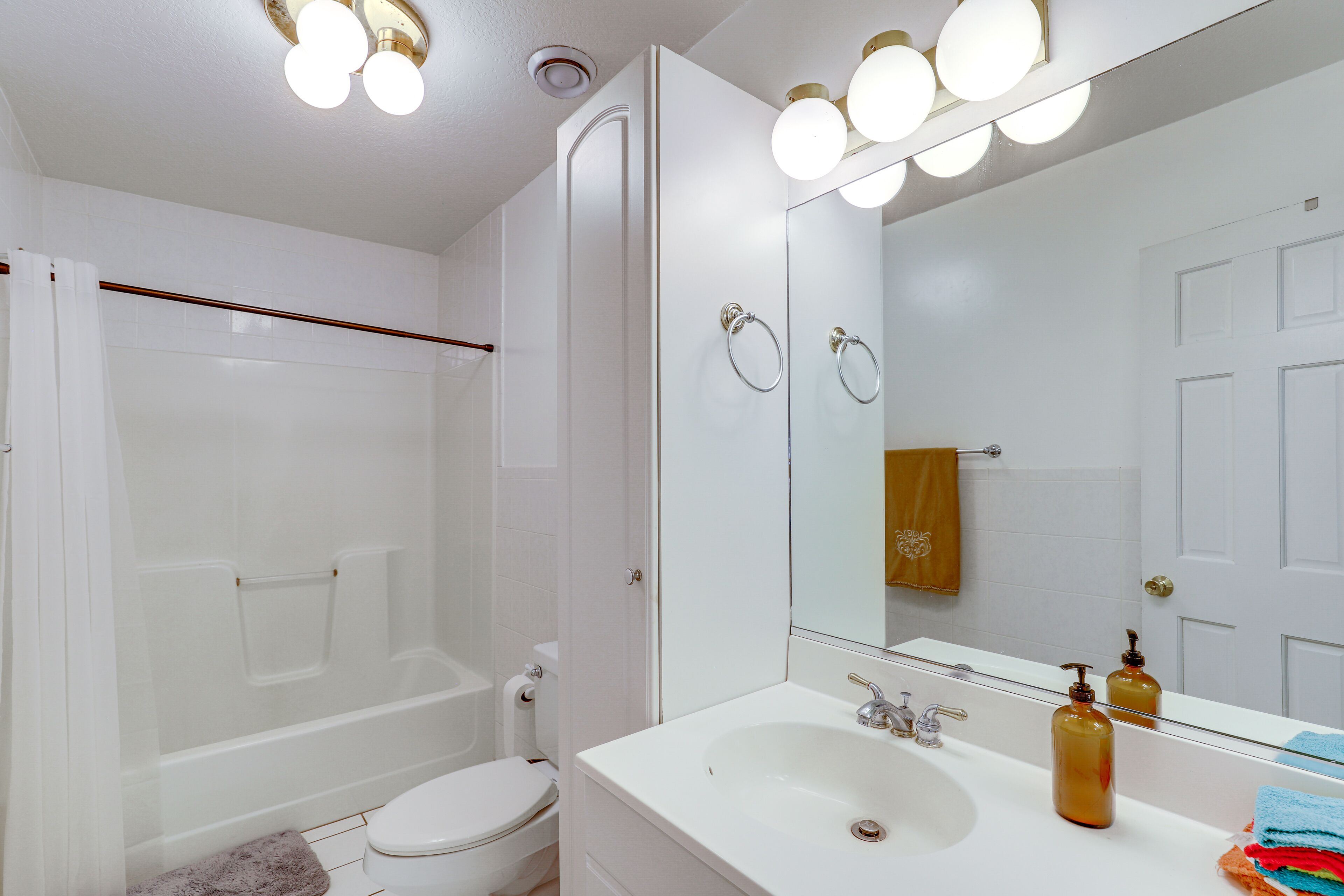 Un bagno moderno con una vasca da bagno bianca, un water, un lavandino con uno specchio e una tenda da doccia.