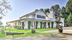 Ein zweistöckiges Haus mit einer Laube, einem Schornstein und einem gepflegten Rasen.