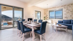 Un coin repas avec une table dressée pour six personnes, un canapé bleu et un mur en pierre.