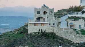 Un bâtiment en pierre, avec une structure rappelant un château, un balcon et une vue sur le paysage.