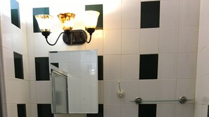 Une salle de bain avec un lavabo blanc, un meuble-lavabo en bois, un miroir, des toilettes et un espace douche.