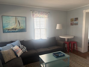 A living room with a sofa, a coffee table, a lamp, a window with blinds, and artwork on the walls. - Downtown, Sleeps 9,  Dog-friendly, Short Walk to the Beach (Cape Charles)