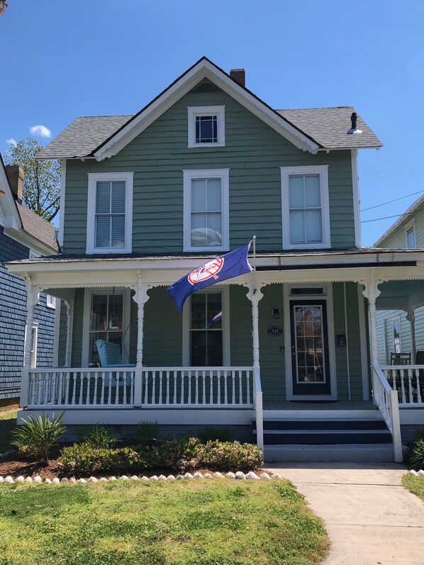 Une maison verte avec un porche et un drapeau.