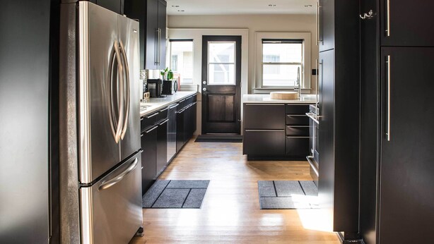 A modern kitchen with stainless steel appliances, dark cabinetry, and a wooden floor. - Updated Tacoma Home w/ Patio: 3 Mi to Downtown (Tacoma)