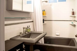 Een badkamer met een wastafel, spiegel en douche.