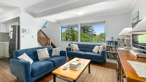 Una sala moderna con un sofá azul, una mesa de centro de madera y una estantería.