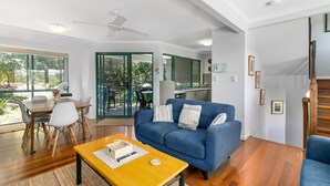 Una sala de estar moderna con un sofá azul, una mesa de centro de madera y una zona de comedor con una mesa y sillas.