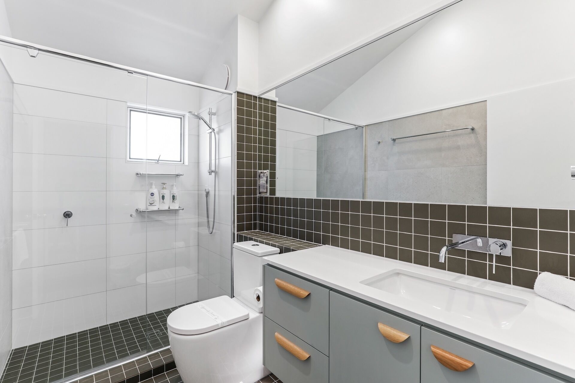 A modern bathroom with a shower, toilet, and sink.