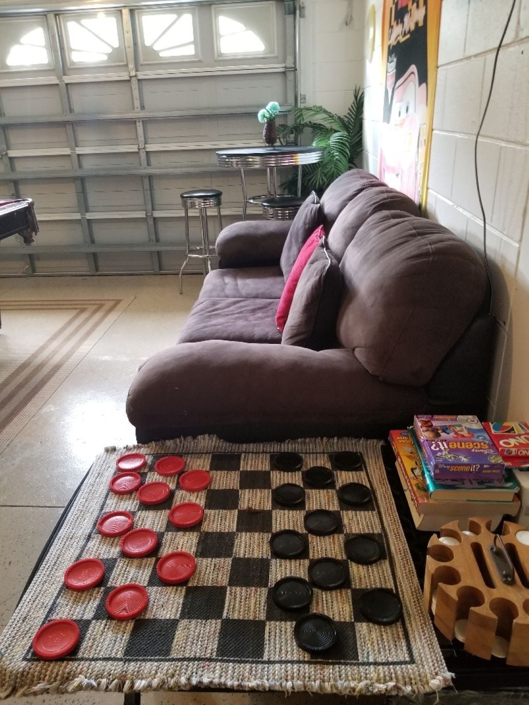 Un salon avec un jeu d’échecs sur le sol à carreaux, un canapé et des livres.