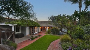 A house with a paved driveway, a small lawn, and various plants and trees. - Rincon Retreat - Casual Beachfront Comfort (Carpinteria)
