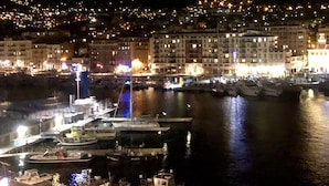 A nighttime harbor with boats docked, a bridge, and illuminated buildings in the background. - Waterfront panoramic sea view with balcony, AC (Nice)