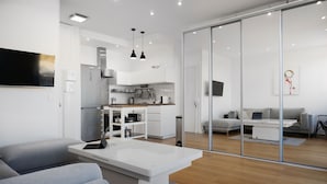 A modern living room with a grey sofa, a white coffee table, and a TV mounted on the wall. - Waterfront panoramic sea view with balcony, AC (Nice)