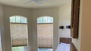 A bedroom with a bed, two windows with blinds, a ceiling fan, and a nightstand. - Private Pool |  Beaches | Golf | Miromar | Baseball No Risk Cancellation (Fort Myers)