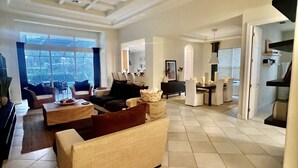 A spacious living room with a high ceiling, large windows, and a view of the outdoors. There are multiple seating areas with sofas and a coffee table. - Private Pool |  Beaches | Golf | Miromar | Baseball No Risk Cancellation (Fort Myers)